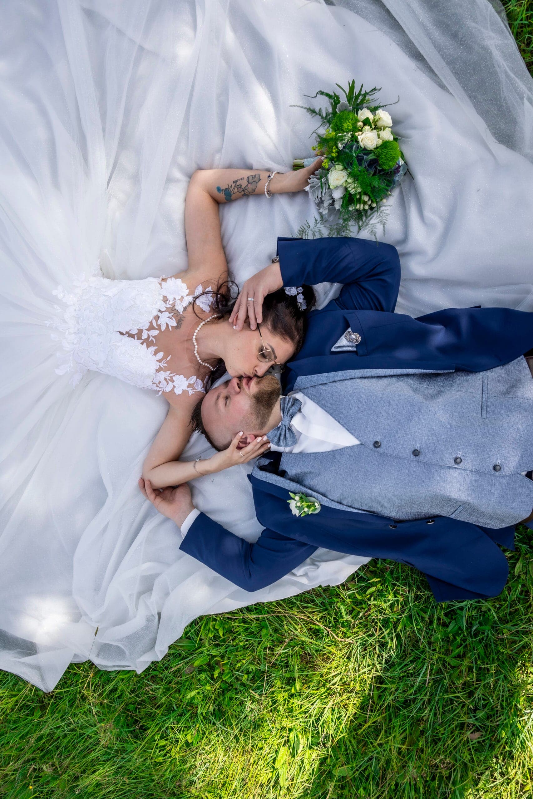 Mariés allongés dans l'herbe lors de leur séance couple